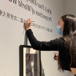 Midori Tanada ’23 touches up the vinyl for the exhibit done by students in Susan Furukawa’s “Narratives of War and Peace” Japanese class.